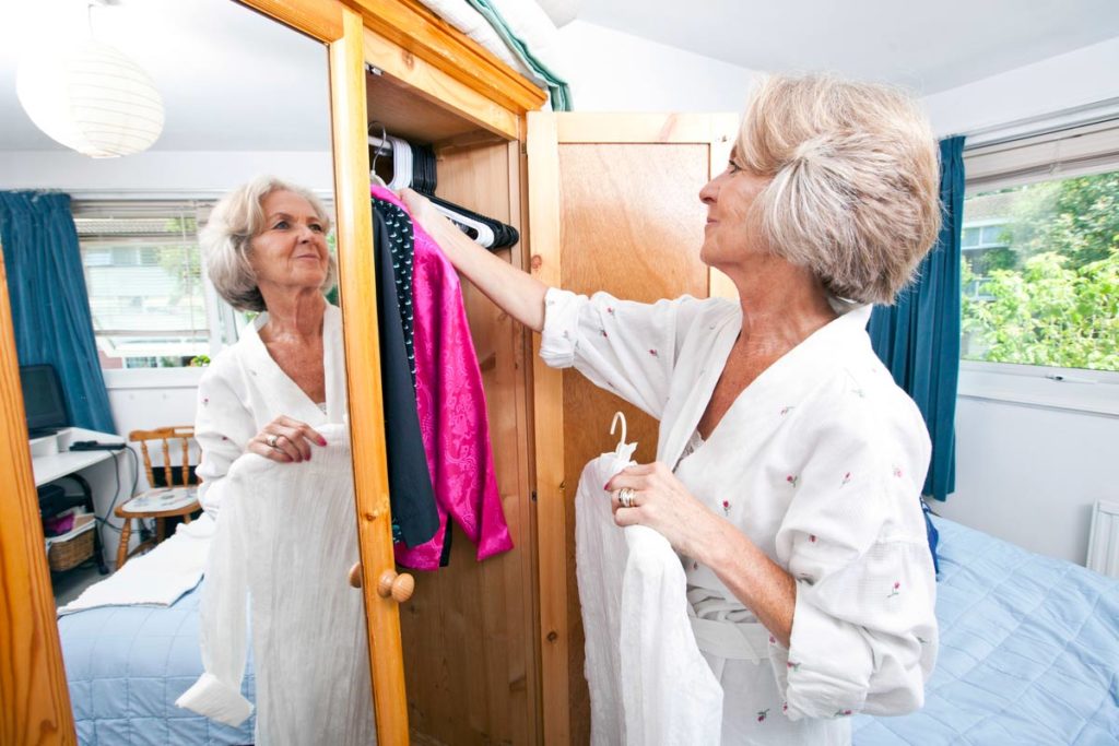 Elderly woman putting close in closet