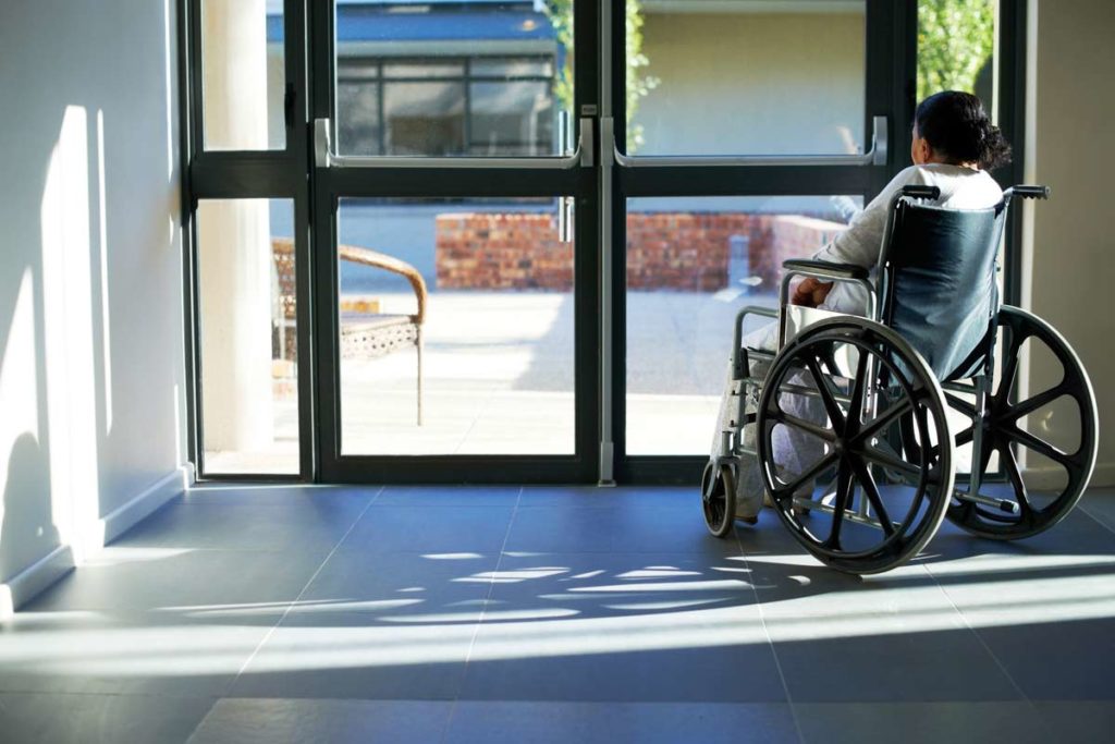 woman in wheelchair looking out sliding doors