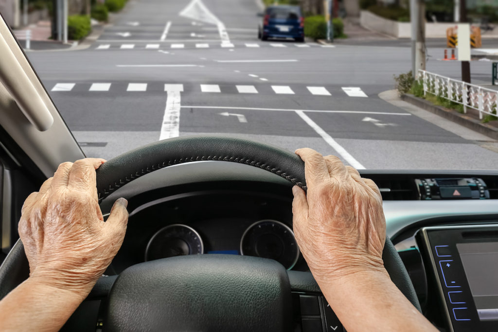 Senior woman driving a car on street in city