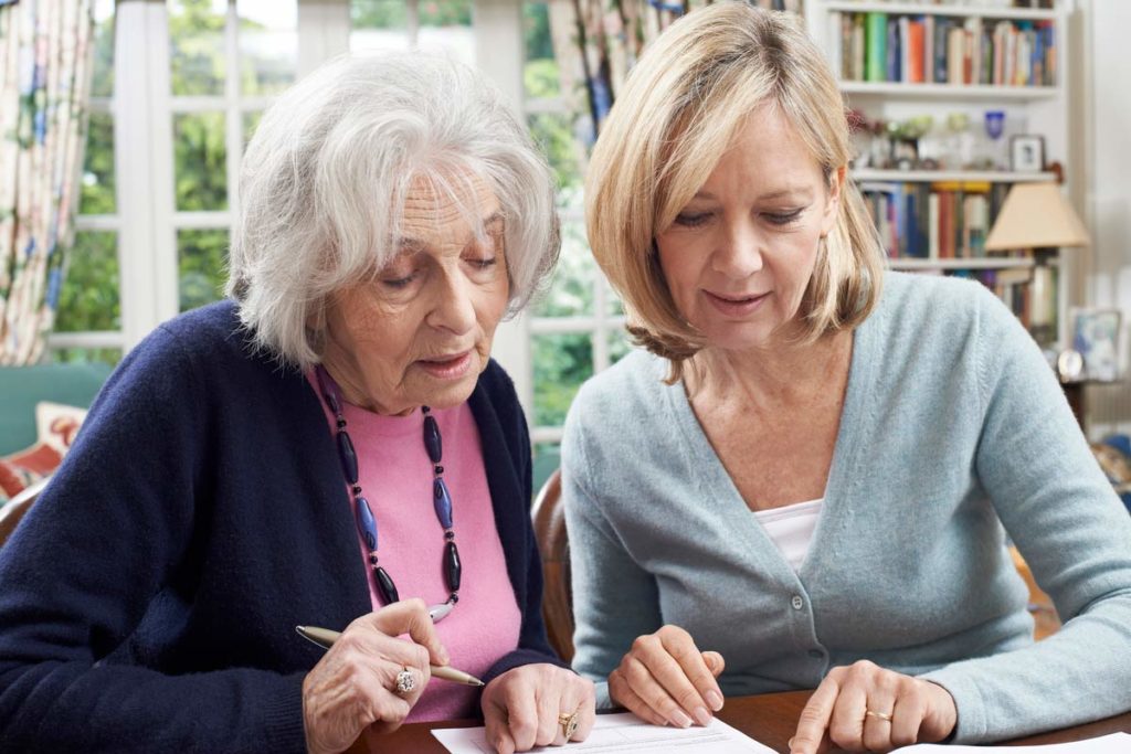 Elderly woman with another woman signing settlement