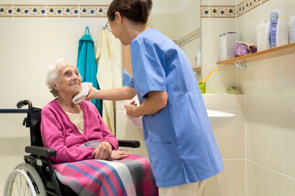 Elderly accompanied by a caregiver in a bathroom