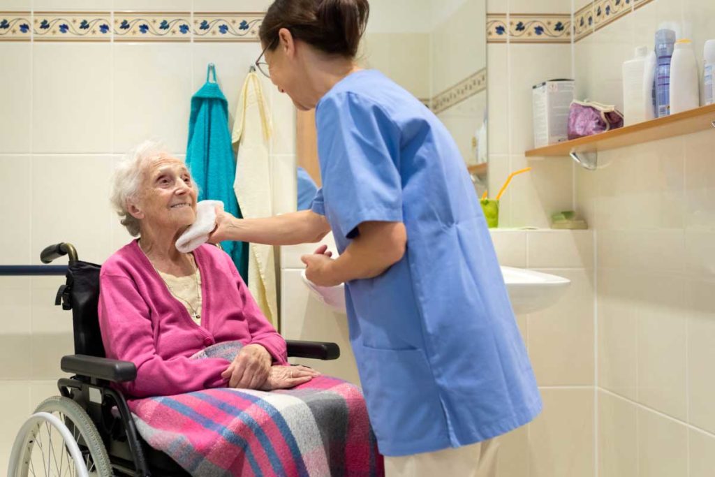 elderly woman in wheelchair with care taker in bathroom