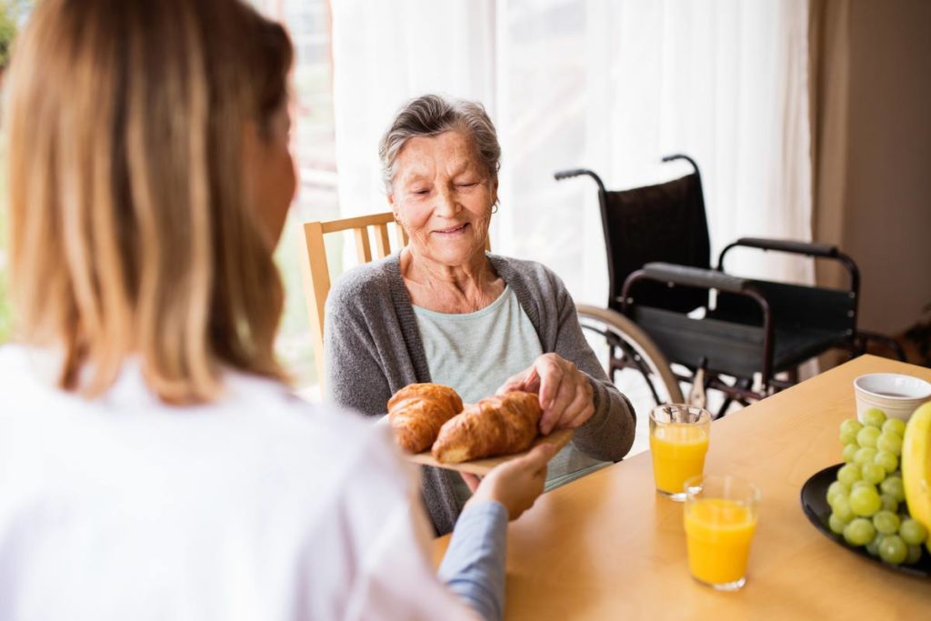 elderly woman having breakfast with caregiver
