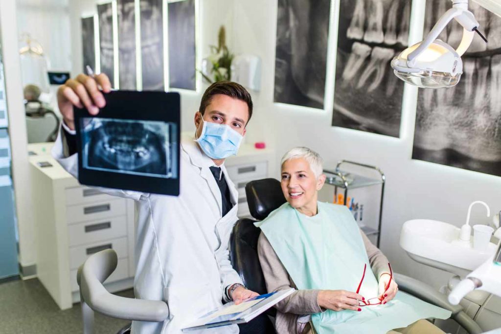 dentist and senior patient looking at an X-ray