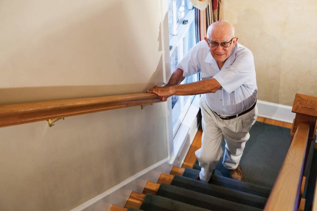 old man walking up the stairs using the railing