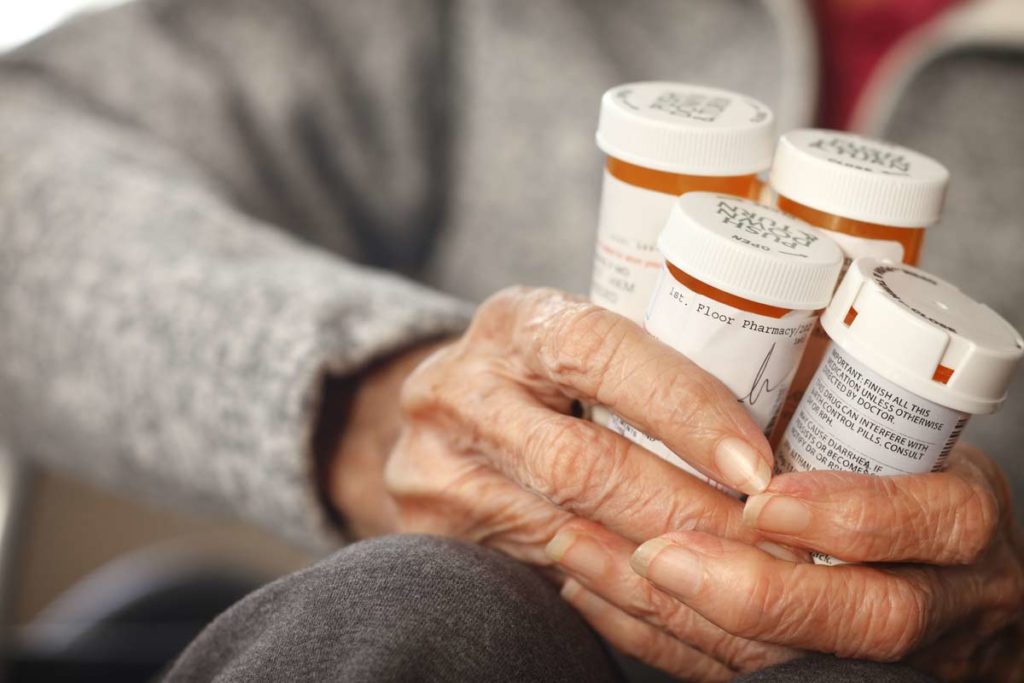 older woman holding medication bottles