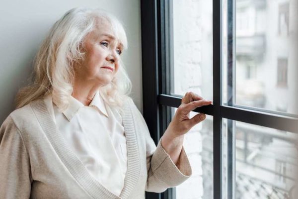 sad elderly woman looking window