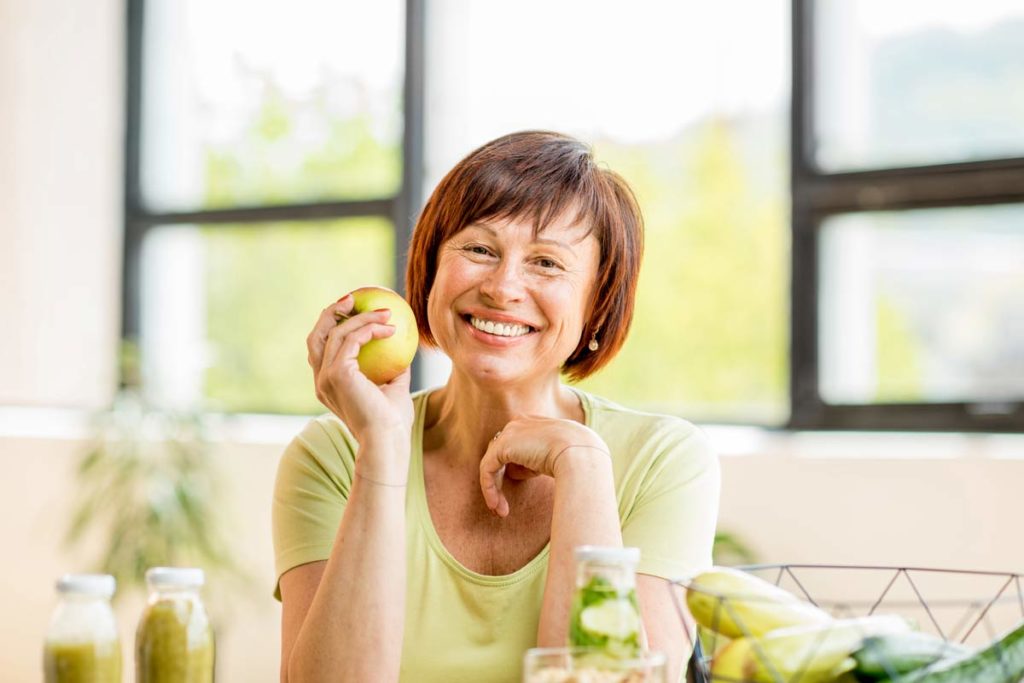 woman smiling with an apple