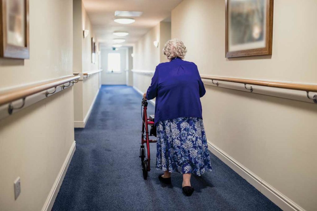 woman walking down a hallway with a walker